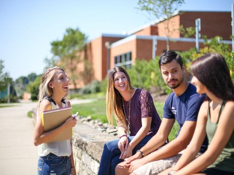 students sitting on the wall outside of smeal building